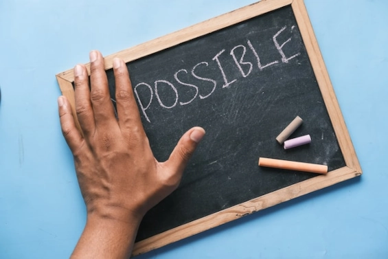 Hand auf einer Kreidetafel mit dem Wort „Possible“, das Vertrauen und das Potenzial für positive Ergebnisse in einer Coaching-Beziehung symbolisiert.